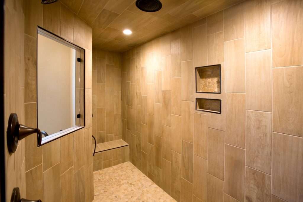 Luxe inloopdouche met houtlook tegels, ingebouwde douchebank, nisjes voor doucheproducten en regendouche – moderne badkamer inspiratie, onderhoudsvriendelijke en warme uitstraling.