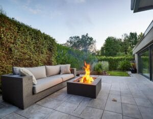 Moderne keramische buitentegels voor terras, grijze terrastegels tuin, vuurtafel en loungeset buiten.