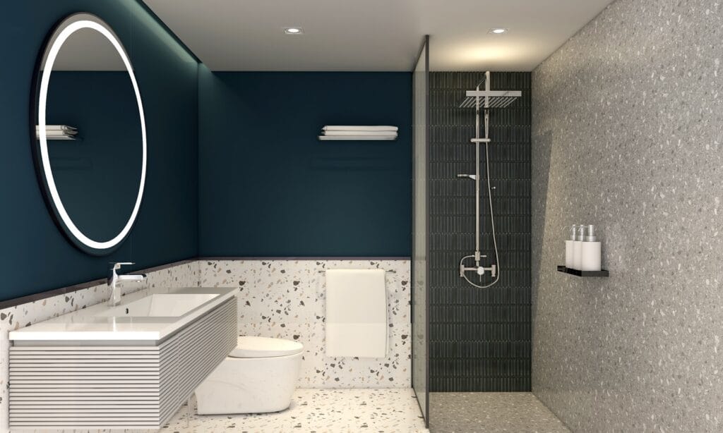 Moderne badkamer met terrazzo vloertegels, een donkerblauwe accentmuur en inloopdouche. Ruime wastafel met ronde verlichte spiegel en eigentijdse uitstraling.