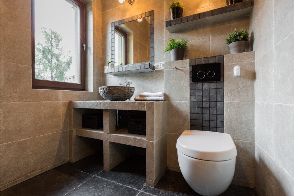 Luxe toilet met grote beige keramische vloertegels en wandtegels, voorzien van een modern hangtoilet en natuurstenen waskom. Perfect voor een stijlvolle en onderhoudsvriendelijke toiletruimte.